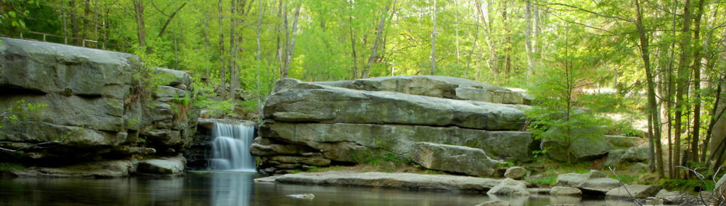 Split Rock Waterfall from downstream. Coxing Kill bridge in the upper left corner and forest seen behind the waterfall