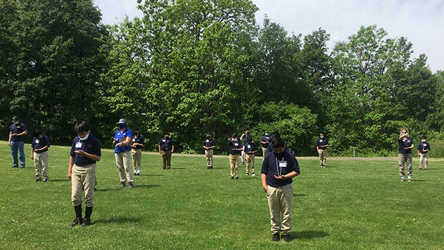 Students in a field wayfinding with compasses.