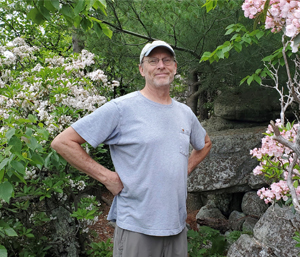Volunteer standing in front of Mountain Laurel on a trail
