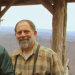 Tom Sarro stands in front of a summer house vista