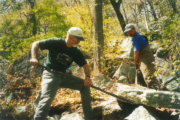 Two people working in a the woods on trail building