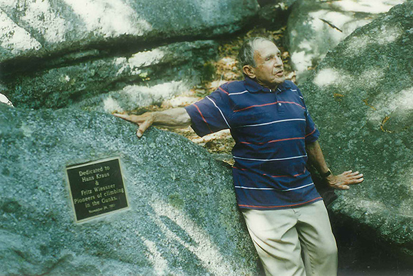 Hans Kraus stands next to Uberfall dedication plaque by the Mohonk Preserve Gunks cliffs