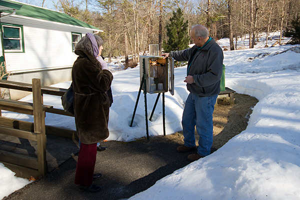 Two people stand outside the Daniel Smiley Research Center in winter looking at a weather data collection station.