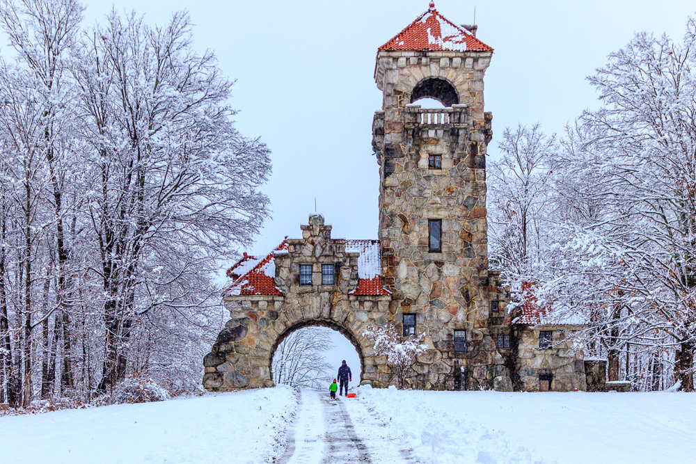 Two people underneath the Testimonial Gateway Tower are sledding during a recent snow fall
