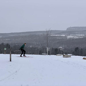 Cross country skiier enjoying a snowy day at Mohonk Preserve with the Shawangunk Ridge and skytop tower in the background