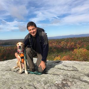 Hiker and dog outside on Shawangunk Ridge enjoying a vista of the Catskill Mountains